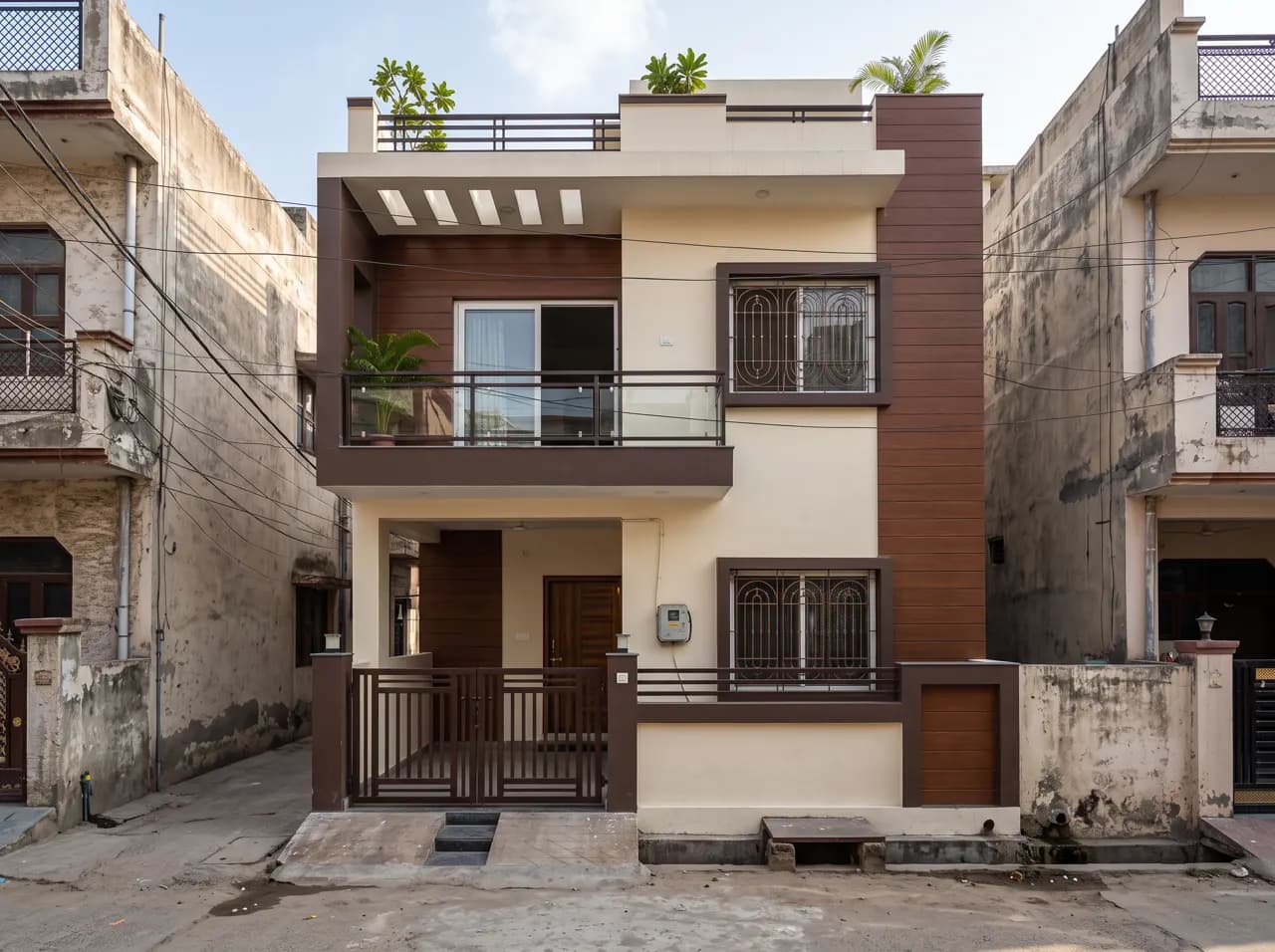 Double floor narrow house elevation with dark brown frame and grilled windows