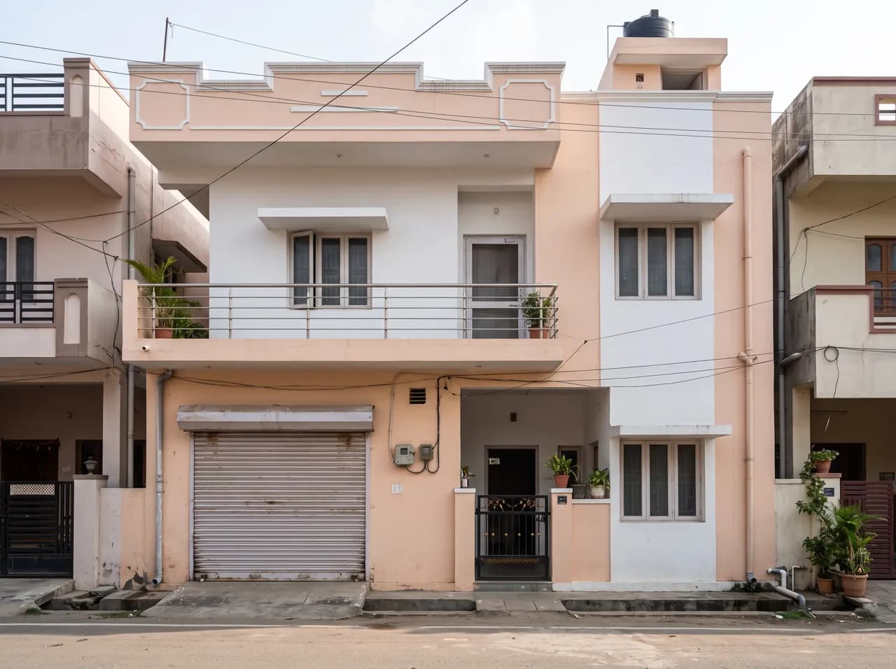 Normal G+1 Indian house front elevation in peach and white with rolling shutter garage