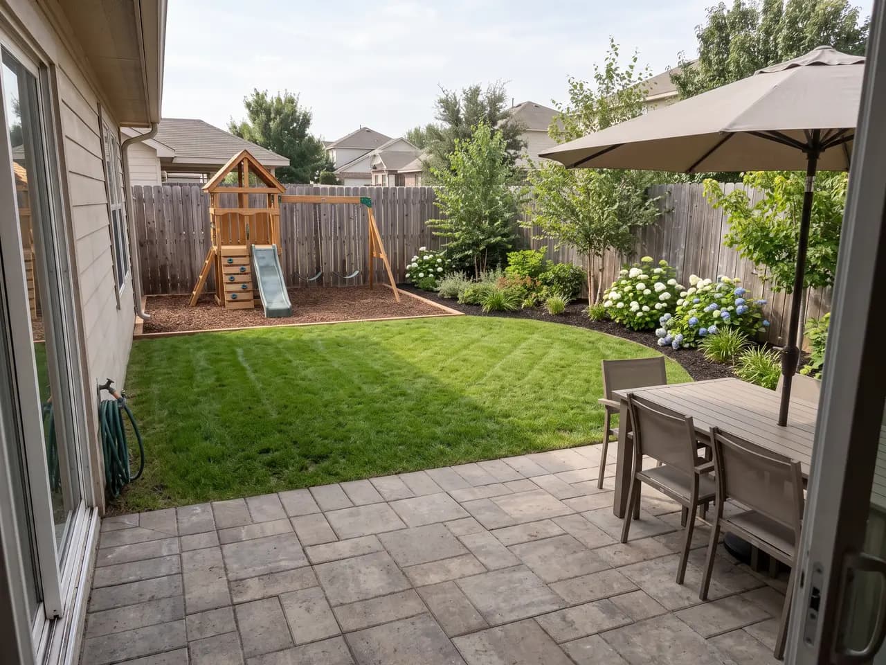 Family backyard design with lawn, timber play structure, planting borders and paver patio — after