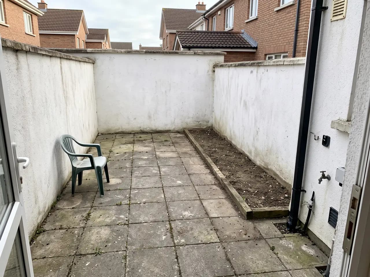 Small walled courtyard redesigned as a Mediterranean patio with terracotta tiles and an olive tree — before